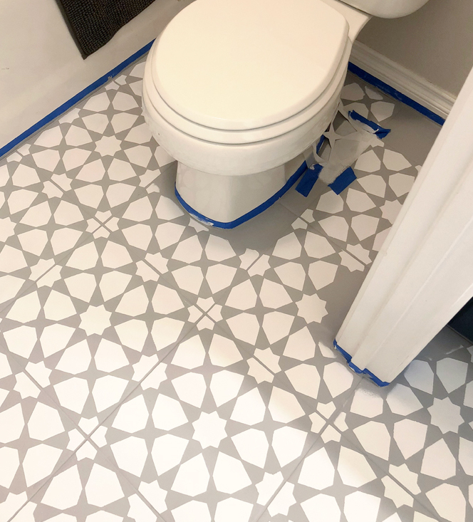 Laying a stencil down around tricky edges on a tile floor.