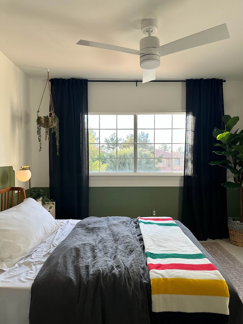 Curtains surrounding a window with plants in the corners of the room.