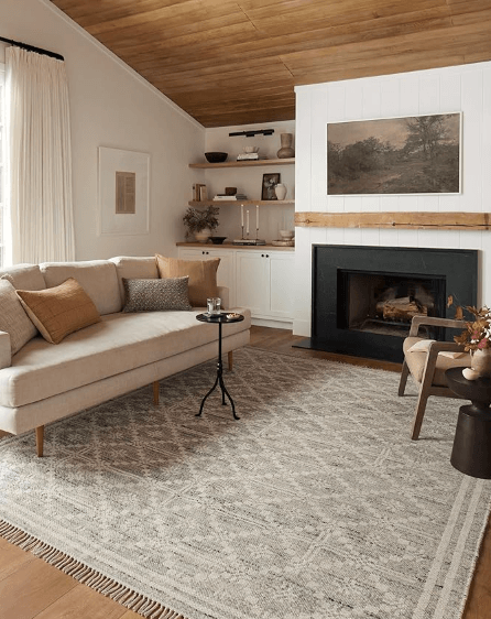 Ivory colored area rug with fringe on the edges staged in a living room.