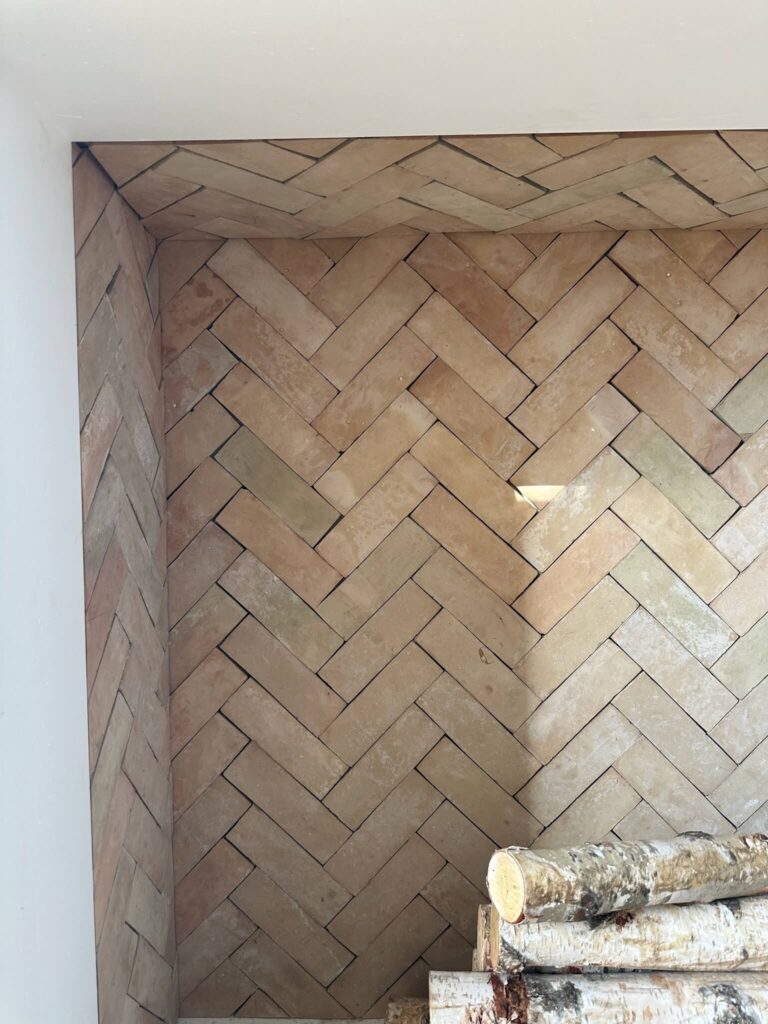 An up close shot of tile inside a fireplace with a herringbone pattern.