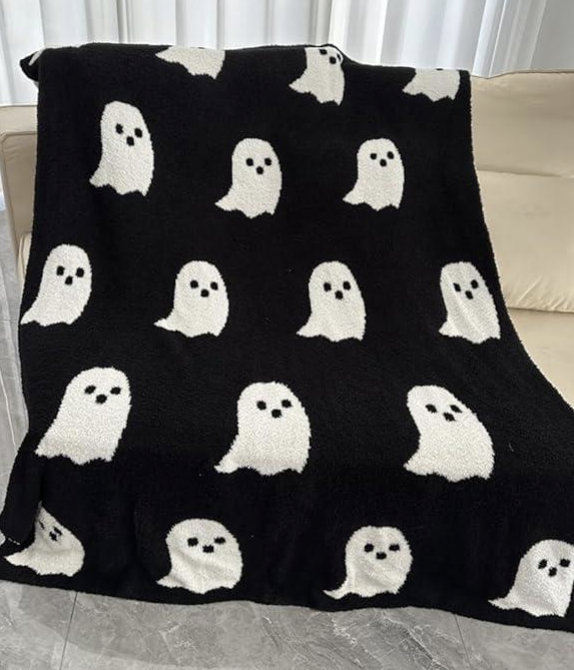 Layered fall home decor with ghost blanket, ivory rug, and plum garland for cozy autumn living.